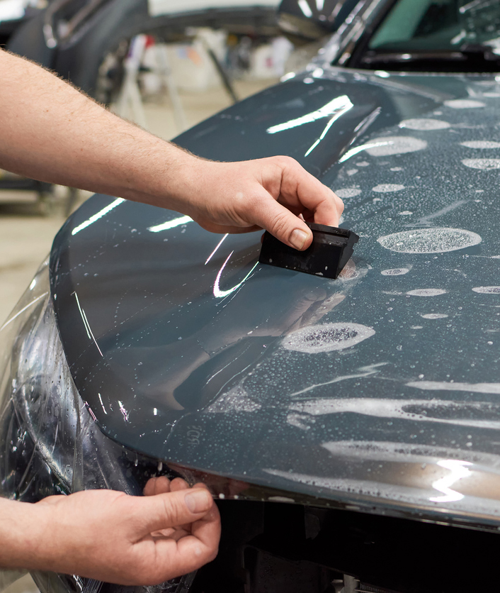Installation of a protective paint and varnish transparent film on the car. PPF polyurethane film to protect the car paint from stones and scratches.